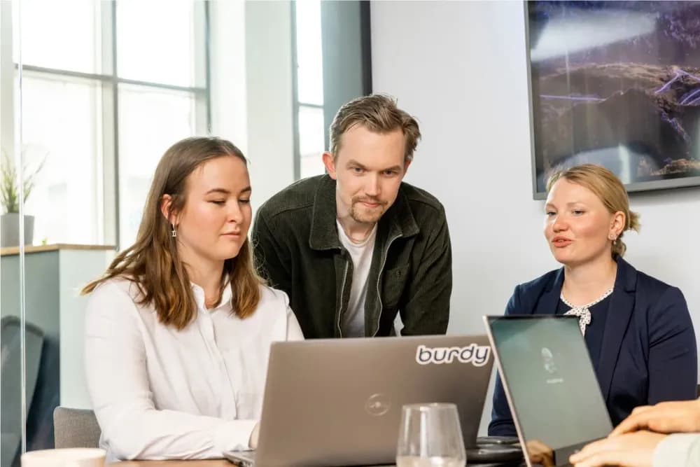 A team of developers are pair programming and discussing the code on their computer 